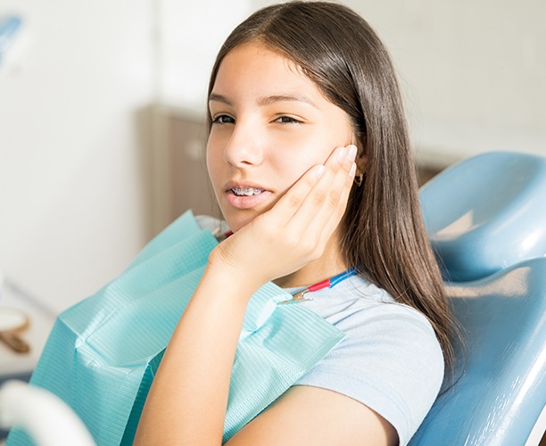 Young woman in need of emergency dental care holding cheek
