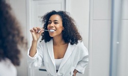 woman in a white bathrobe brushing her teeth
