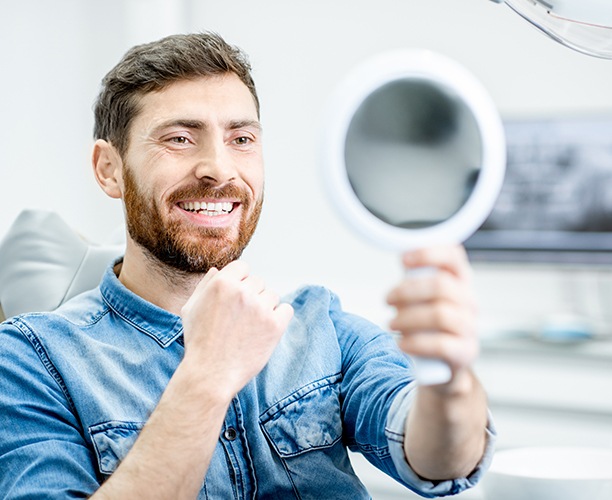 Man looking at his healthy smile in the mirror