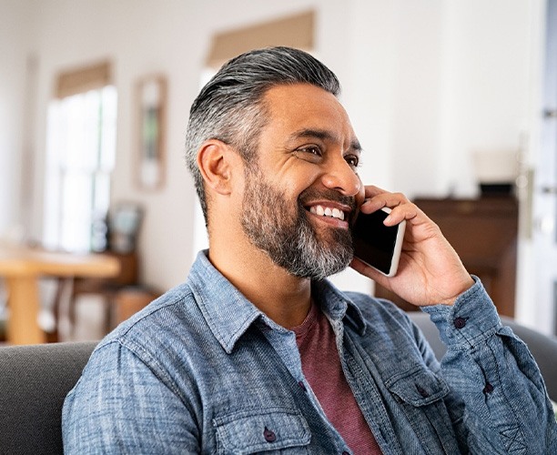 Man smiling while talking on phone at home