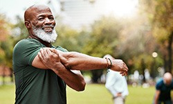 Man in green shirt outside stretching with friends