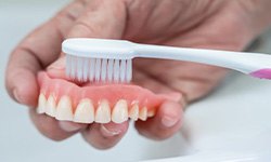 Denture being brushed