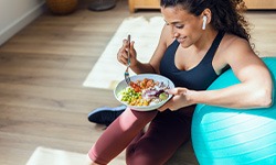 Woman leaning on medicine ball eating salad