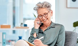 Woman talking on phone and writing in notebook
