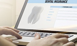 person filling out dental insurance information on a laptop 