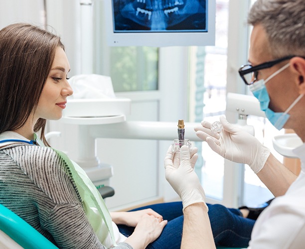 dentist showing a dental implant to a patient 