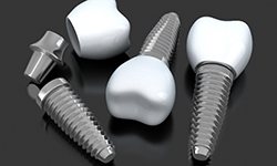three dental implant posts with abutments and crowns lying on a flat surface 