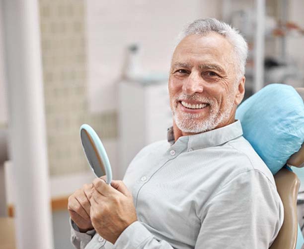 dentist showing a patient a model of a dental implant in the jaw 