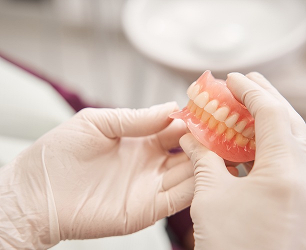 White gloved hands holding complete set of dentures