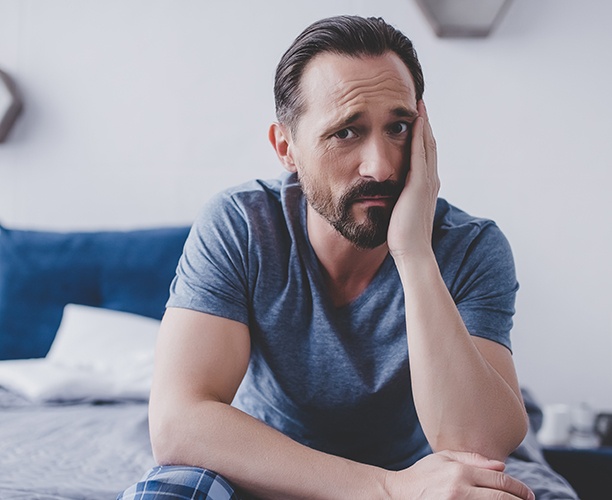 Man in need of emergency dentistry holding jaw in pain