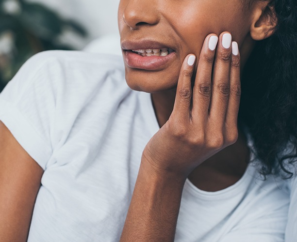 Patient in need of emergency dentistry holding jaw in pain