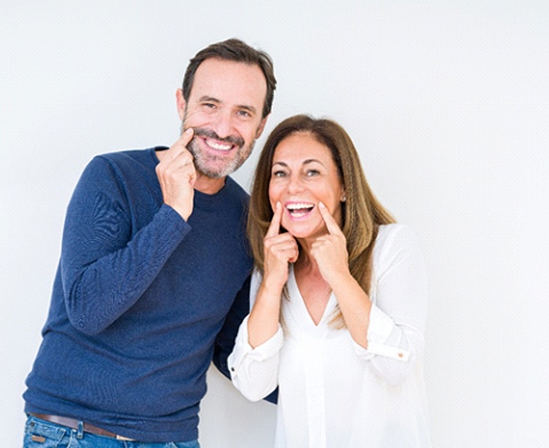 man and woman pointing to their smiles