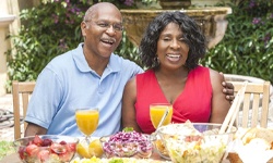 man and woman sitting at a table with various foods