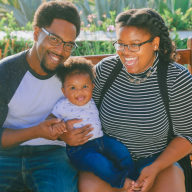 Mother father and child smiling on a bench outdoors