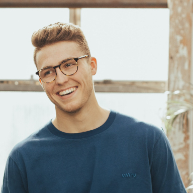 Man with blue shirt and glasses smiling