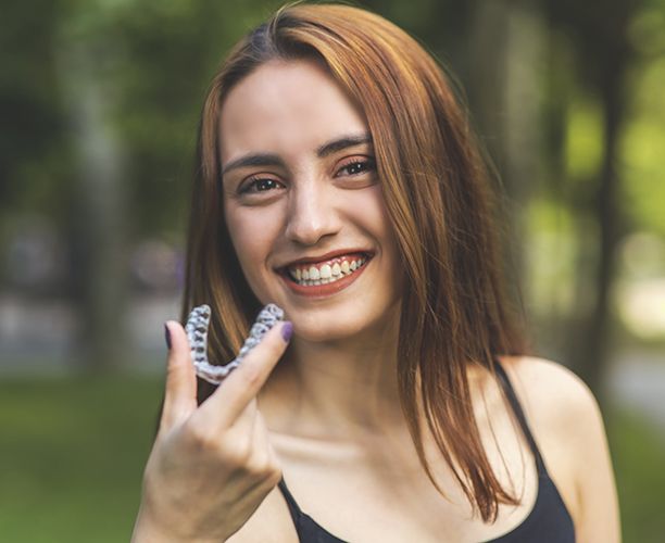 Smiling woman placing an Invisalign tray