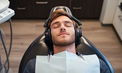 Dental patient relaxing in treatment chair, wearing headphones