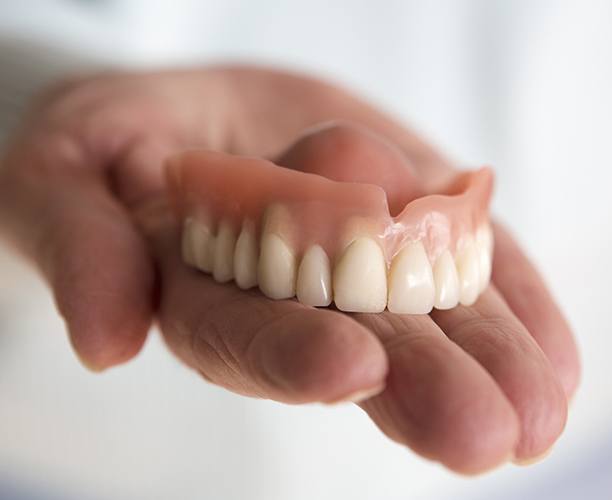 Hand holding a full denture