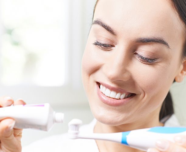 Woman brushing teeth to maintain porcelain veneers