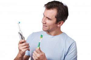 A man compares an electric toothbrush to a traditional one.