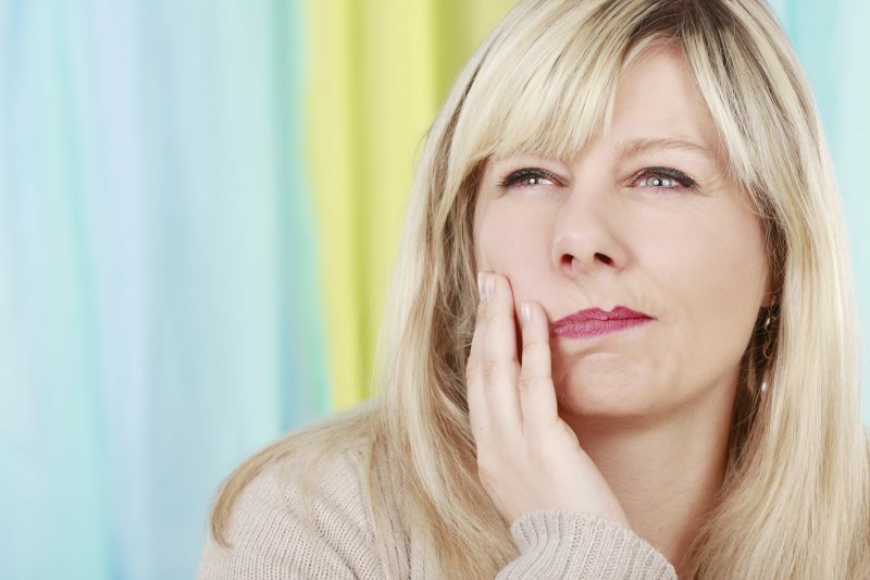 woman holding her jaw in pain