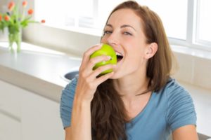 Woman in blue shirt eating apple