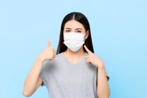 young woman wearing face mask and giving thumbs up to dentist in Las Cruces 