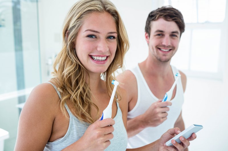 Couple smiling while brushing their teeth