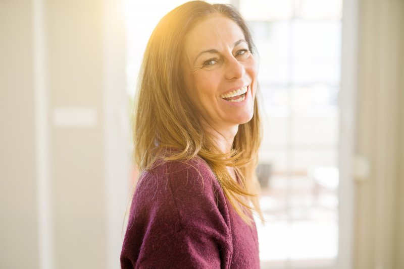 a middle-aged woman wearing a purple sweater and showing off her healthy smile