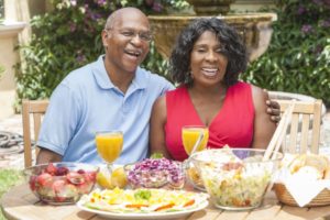 couple with dental implants in Las Cruces sitting at a table with various summer foods 