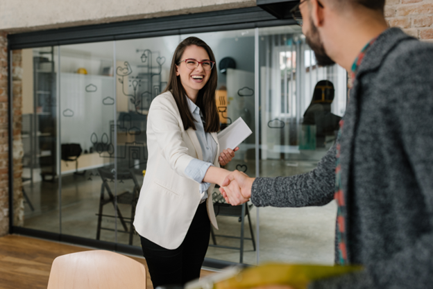 person smiling while shaking other person’s hand