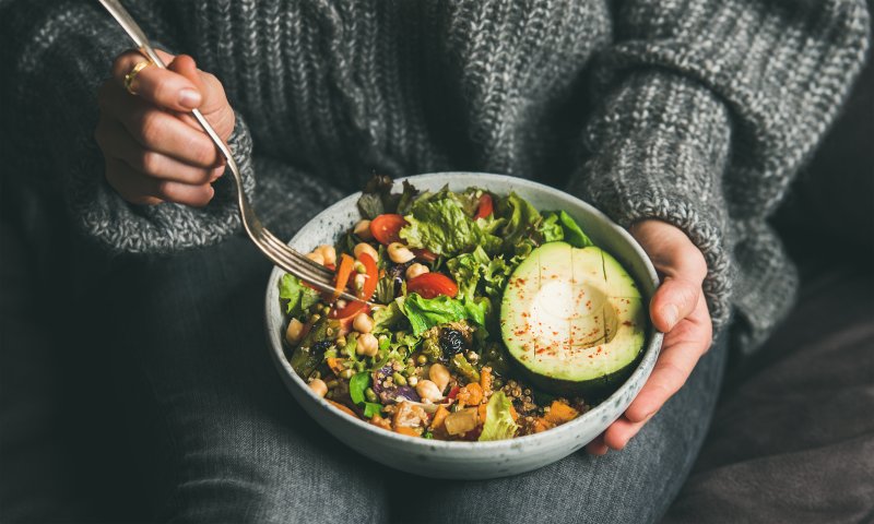 A bowl of healthy summer salad with tomatoes, salmon, leafy greens, and avocado