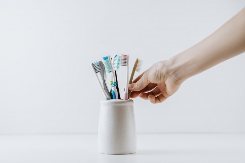 Hand reaches for toothbrush in holder