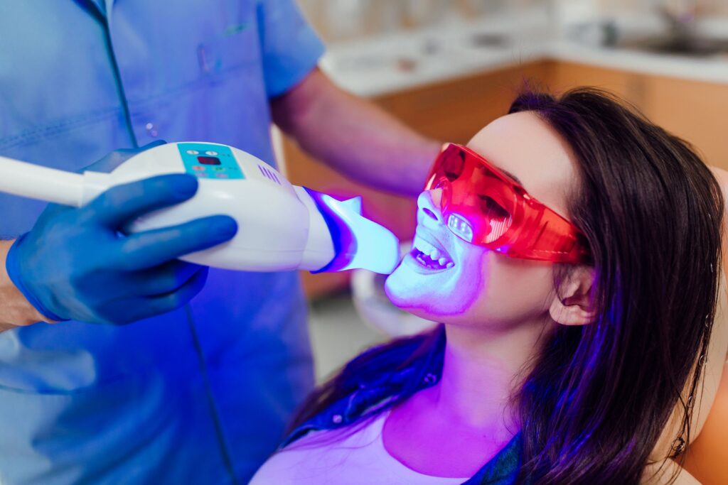 Dentist applying UV light to whiten woman's teeth