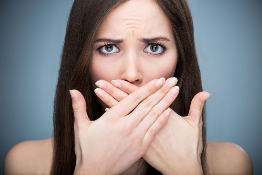 Woman putting hands in front of mouth to block bad breath