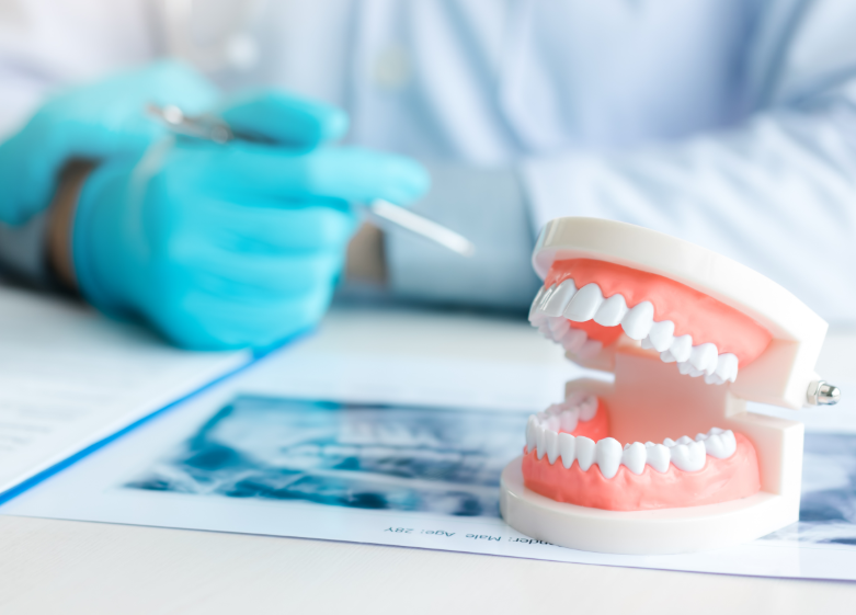 Dentures on table with dentist's hand in the background