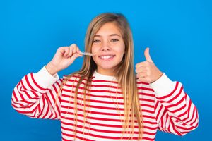 Teenage girl holding Invisalign and giving a thumbs up